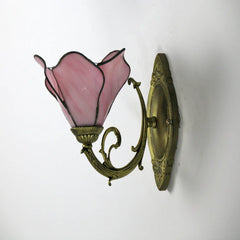 Wall-mounted lamp with pink glass shade and gold metal fixture on a white background