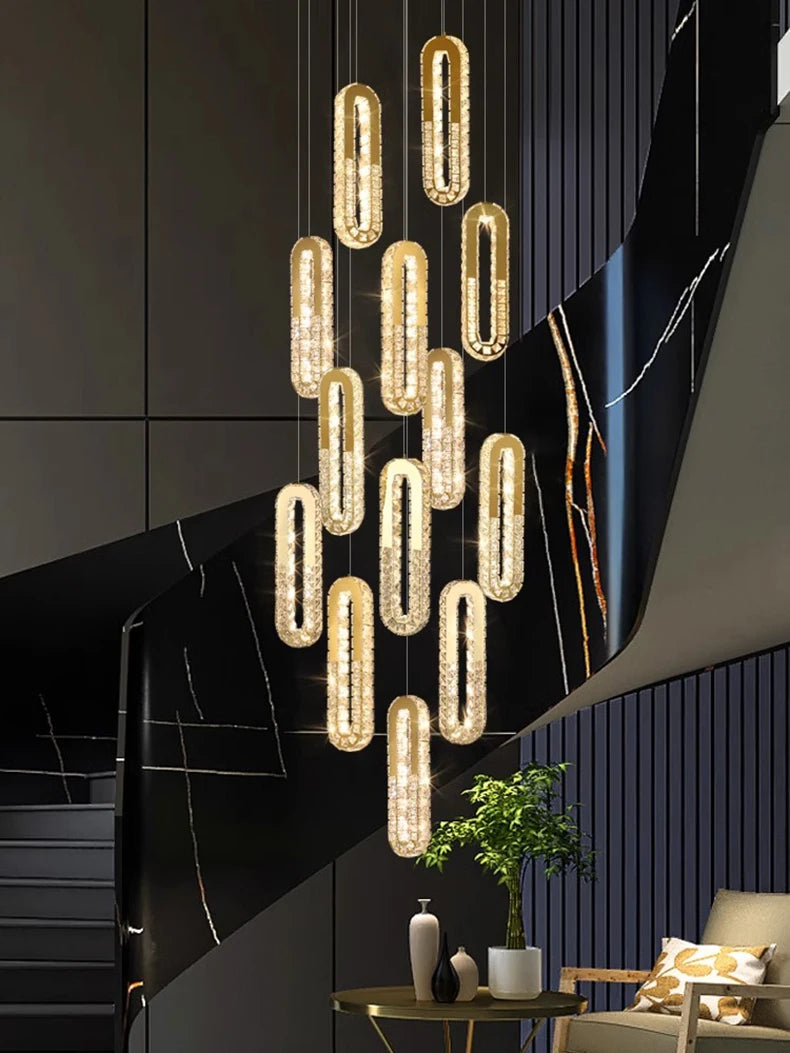 Modern chandelier hanging in a stylish interior setting with dark walls and a plant.