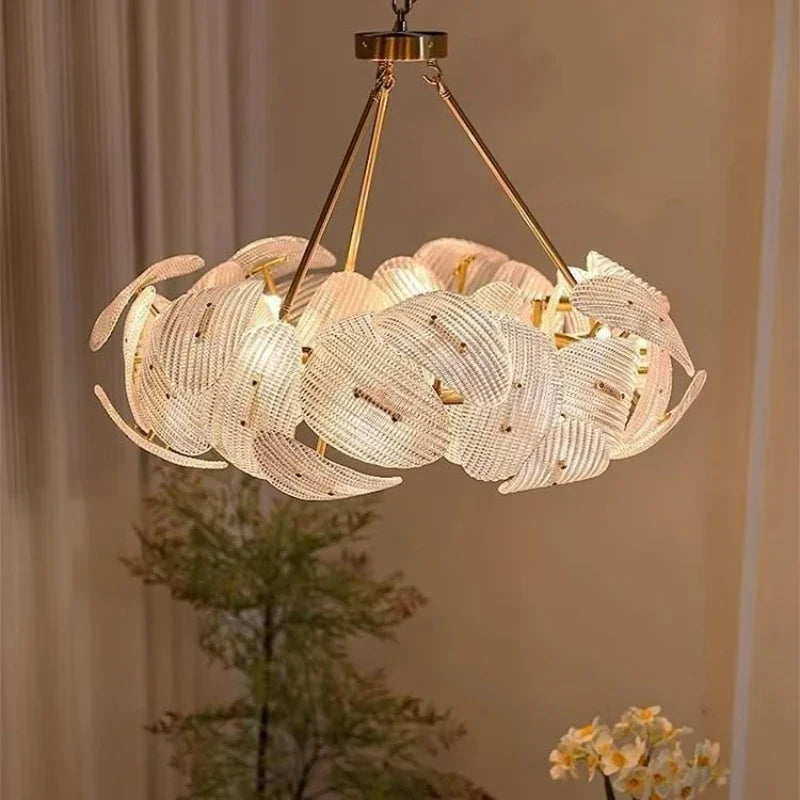 A round, woven pendant light with a floral-inspired design in a polished gold finish, hanging from a ceiling.