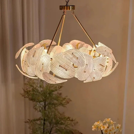A round, woven pendant light with a floral-inspired design in a polished gold finish, hanging from a ceiling.
