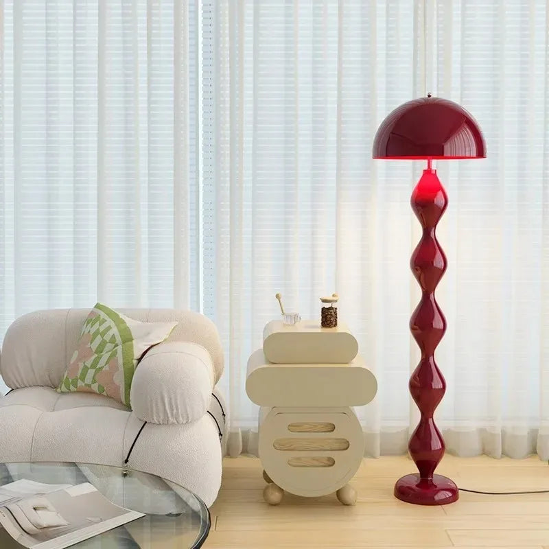 Red mushroom floor lamp with a segmented base in a room with a white chair.