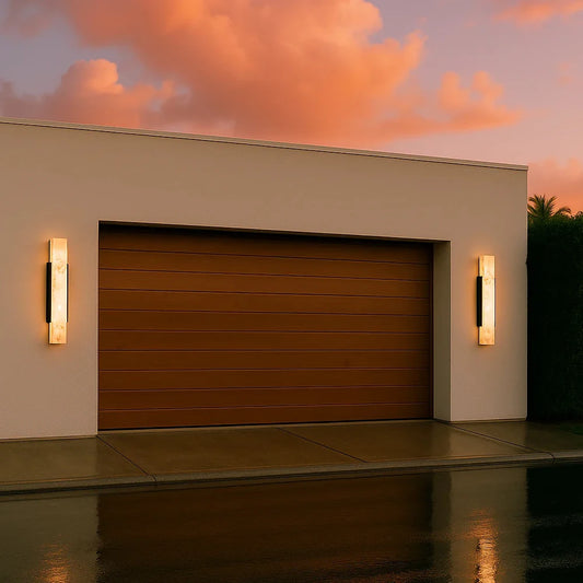 Modern outdoor wall light with a marble-effect diffuser and stainless steel frame, illuminated against a twilight sky.