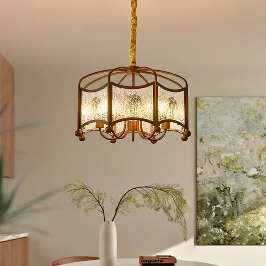 A brushed gold pendant light with a rounded, tiered frame featuring frosted glass panels with a subtle floral pattern, suspended by a golden braided cord.