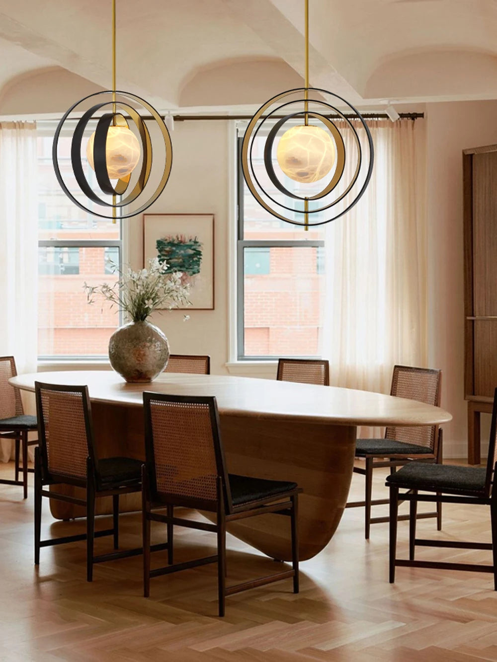 Dining room with modern oval table and chairs, featuring decorative pendant lights.