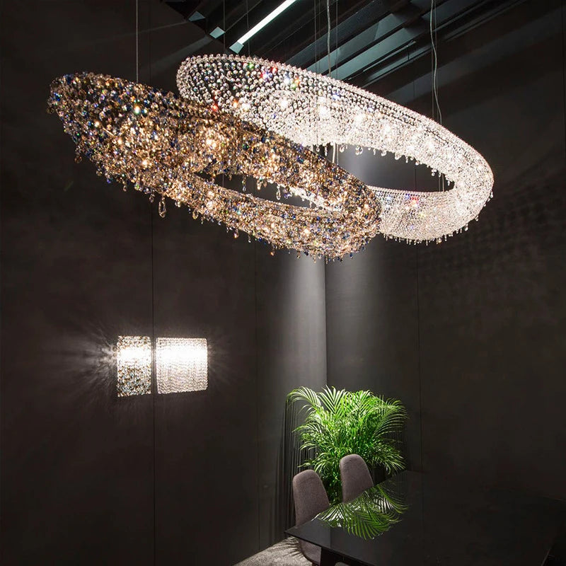 Two intertwined gold and silver ring crystal chandeliers hanging in a dark room, casting light patterns.