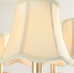 Beige lampshade with decorative trim on a light background.
