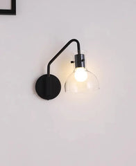 Modern wall-mounted light fixture with a black arm and base on a white wall.