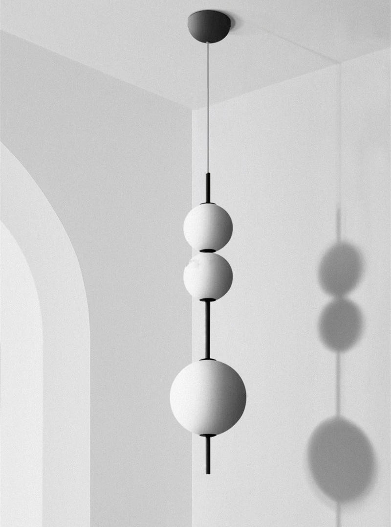 Modern pendant light with three spherical shades hanging from a ceiling.