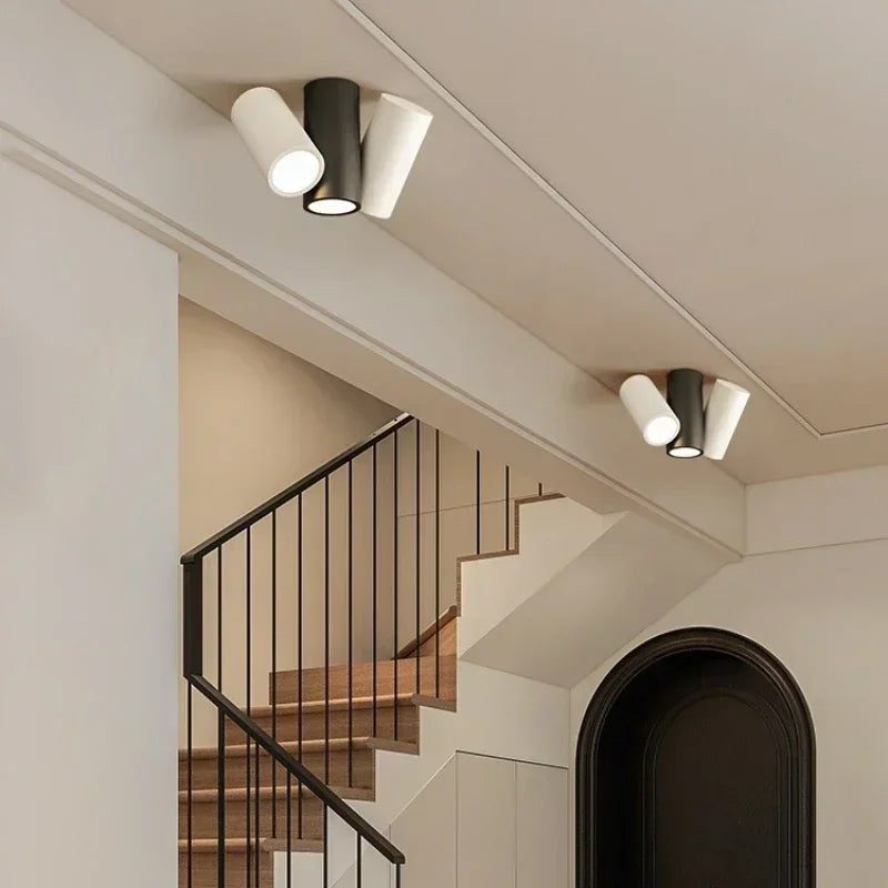 Three cylinder spotlights, two white and one black, arranged in a cluster on a ceiling.
