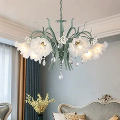 Green floral ceramic chandelier with crystal accents, hanging in a room with light gray walls and curtains.