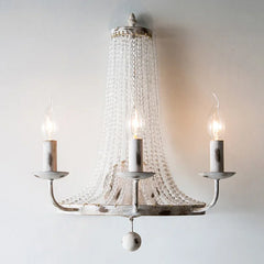 Decorative chandelier with three candle-style lights on a plain background
