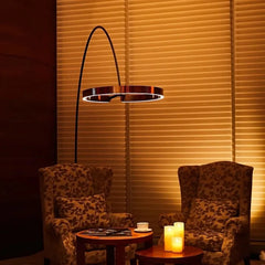 Two patterned armchairs with a small table and floor lamp against a wall with horizontal blinds.