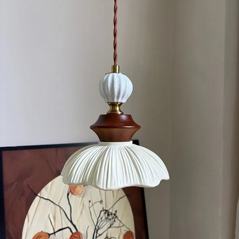 Cream-style bell-shaped pendant light with a ribbed resin shade and walnut accents, hanging against a neutral wall.