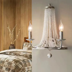 Wrought iron wall sconce with beaded design in a bedroom setting