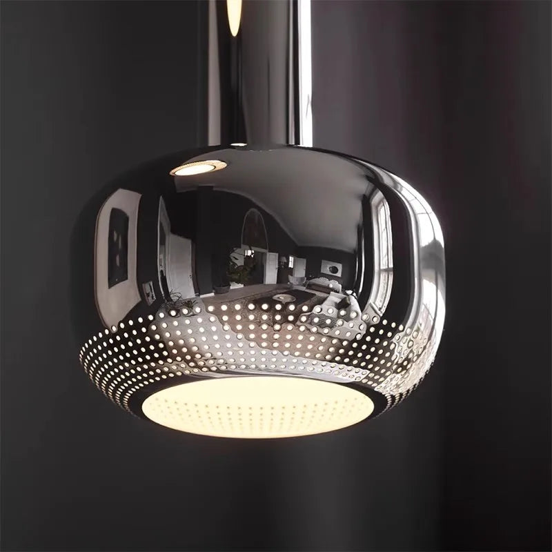 Chrome pendant light with perforated design on a black background