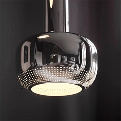 Chrome pendant light with perforated design on a black background