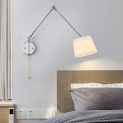 Wall-mounted lamp in a bedroom setting with a bed and headboard.