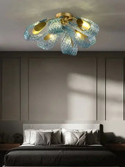 Ceiling light fixture with blue glass shades and gold accents in a bedroom setting.