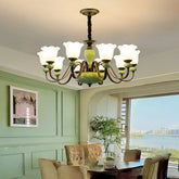 A green and cream ceramic floral pendant light with a polished chrome finish hangs from the ceiling in a dining room setting.