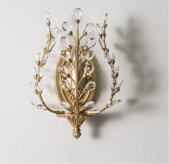 Decorative wall sconce with gold and crystal design on a light gray background.
