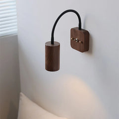 Wooden wall lamp with black cable on a white wall