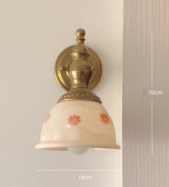 Wall-mounted light fixture with decorative glass shade on a neutral background