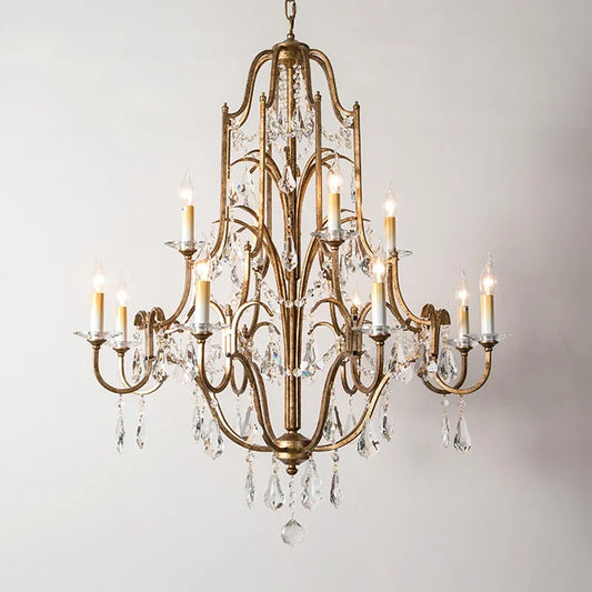 A close-up view of a gold candelabra chandelier adorned with clear crystals against a white background.