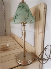 Table lamp with a green floral-patterned shade on a wooden surface.