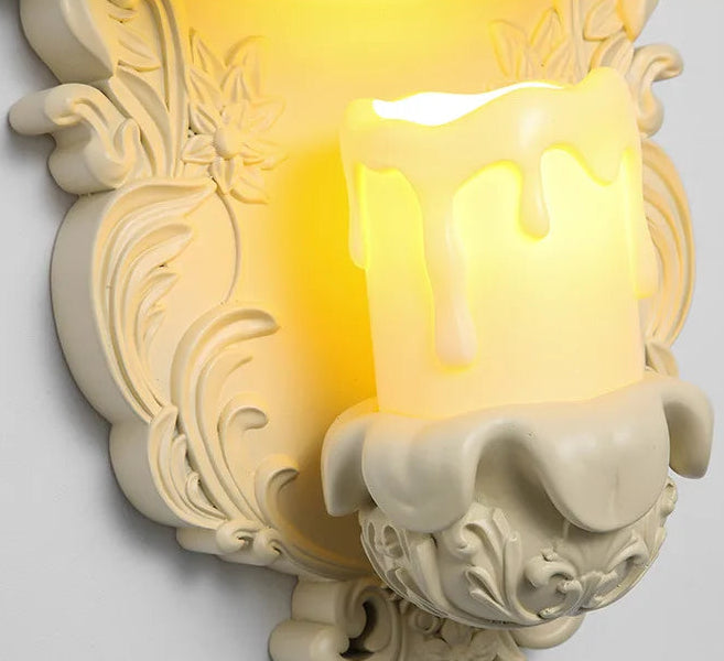 Detailed view of the ornate resin base of a wall sconce with a faux candle light.