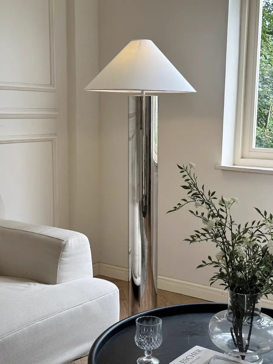 Modern floor lamp in a living room setting with a white sofa and decorative items.