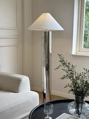 Modern floor lamp in a living room setting with a white sofa and decorative items.