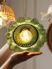 Decorative green glass light fixture held by a hand with blurred background