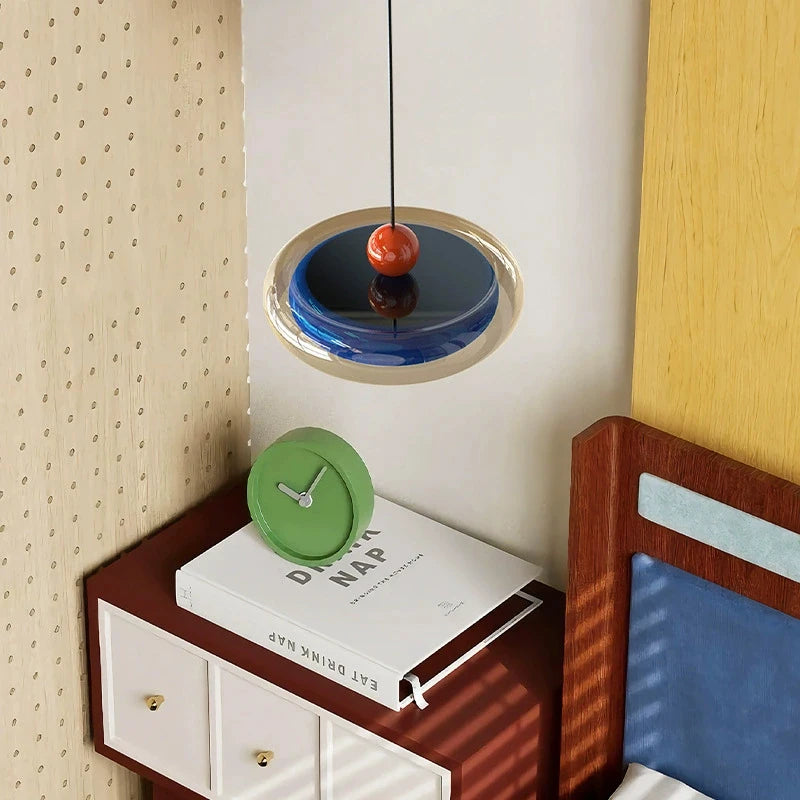 Close-up view of the blue oval pendant light with red accent, showing its layered design.