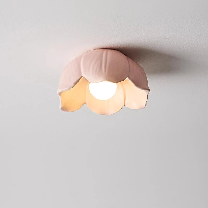 Close-up of a pink ceramic flower-shaped semi-flush ceiling light with a frosted finish, illuminated by an internal LED bulb.