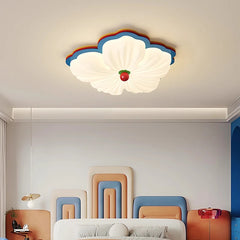 White flower-shaped flush mount ceiling light with multicolor accents above a bed with colorful headboards.