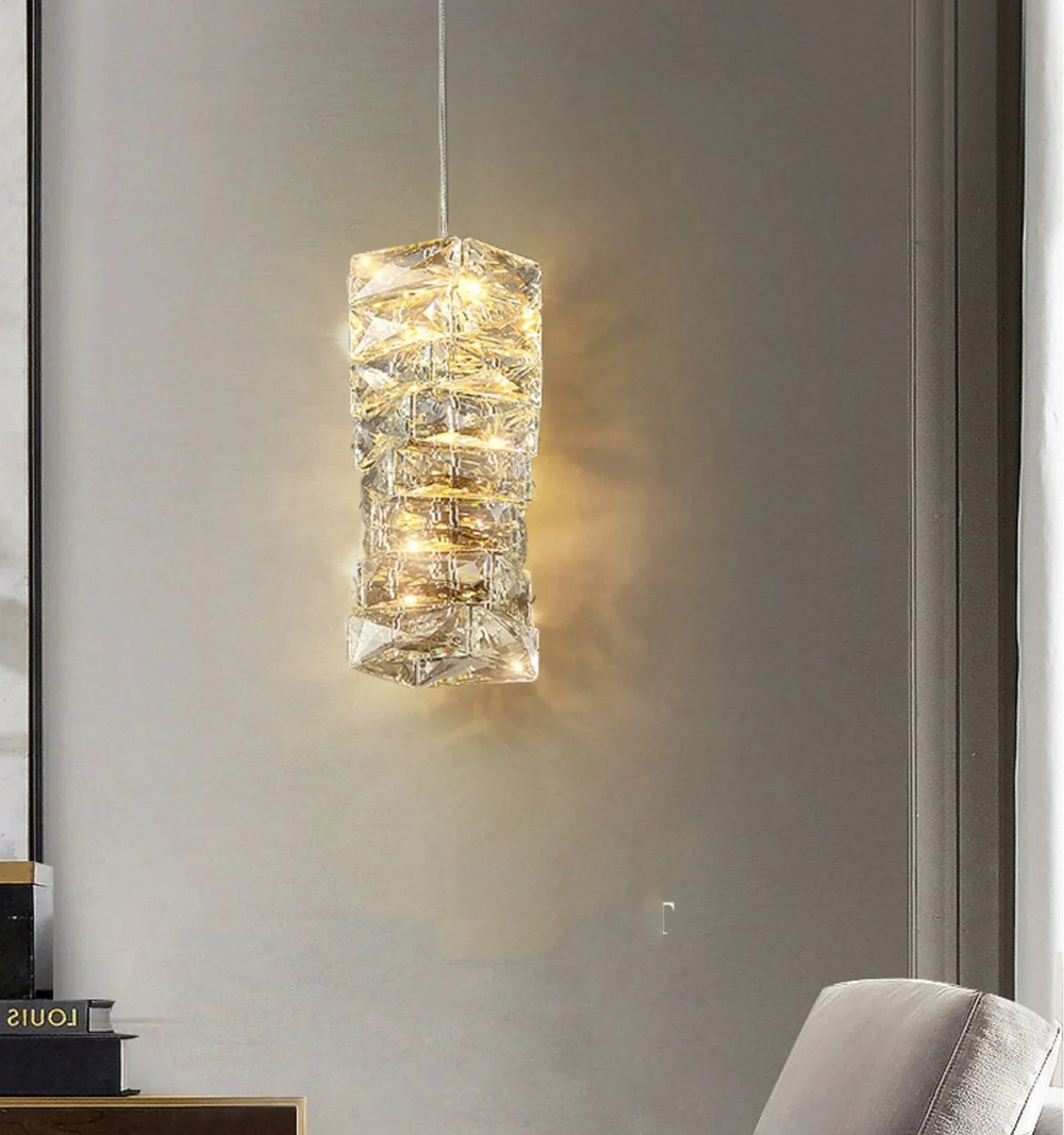 Modern pendant light fixture hanging in a room with a gray wall and a chair.