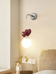 Wall-mounted light fixture with heart-shaped design in a bedroom setting.