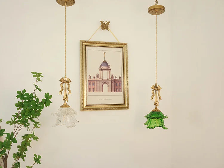 Decorative wall art with gold frame and hanging glass lamps on a light beige wall.