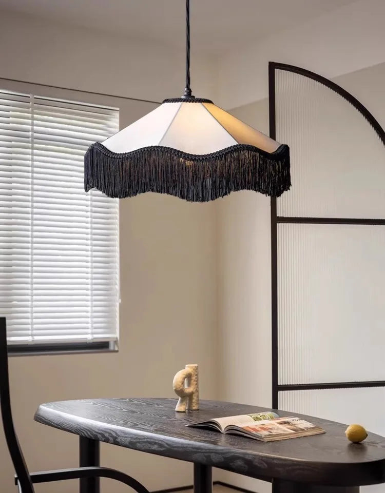 Modern pendant light hanging above a dining table with decor items.