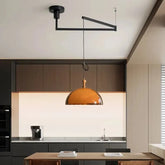 Kitchen island pendant light with an amber glass dome shade and black adjustable arm