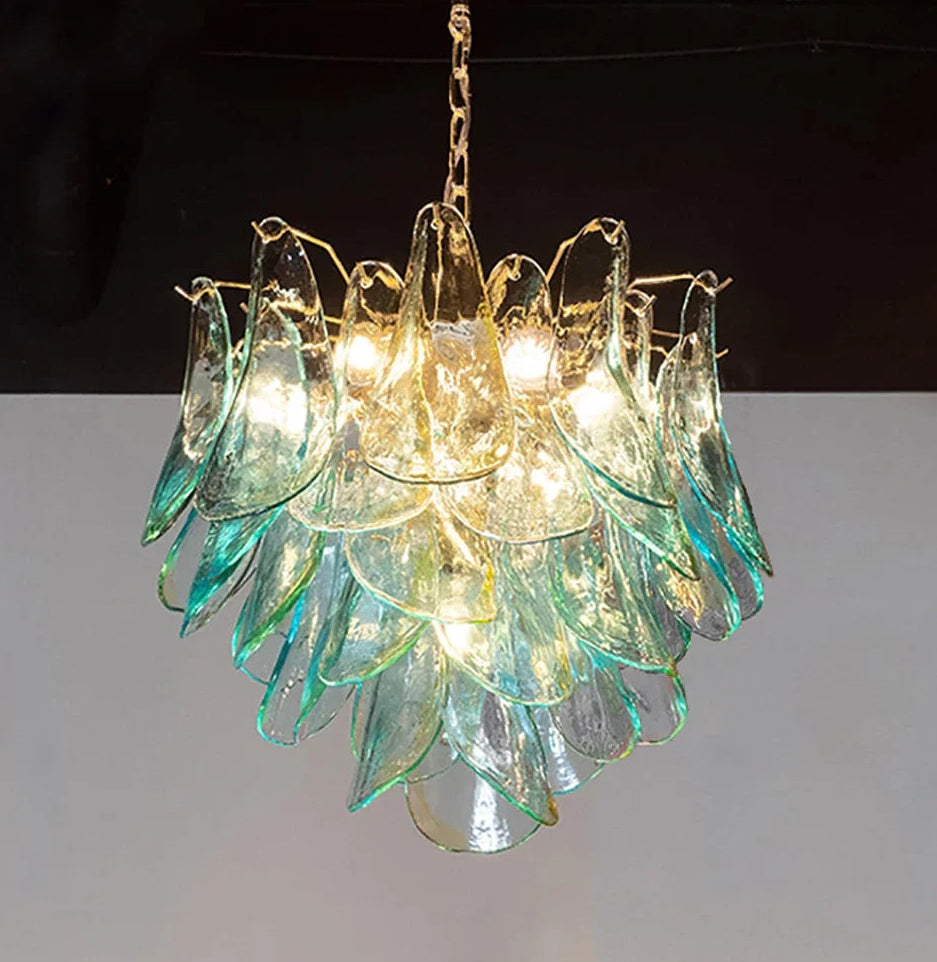 Decorative chandelier with green and gold glass elements on a plain background
