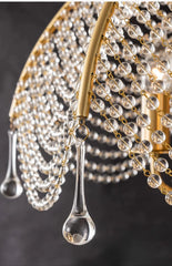 Close-up view of clear teardrop crystals and crystal beads on a gold chandelier frame.