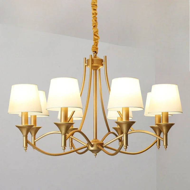 Gold chandelier with white lampshades on a plain background