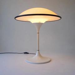 Modern table lamp with a white base and yellowish light on a plain background