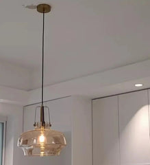 Pendant light with glass shade hanging in a room with white walls and ceiling.