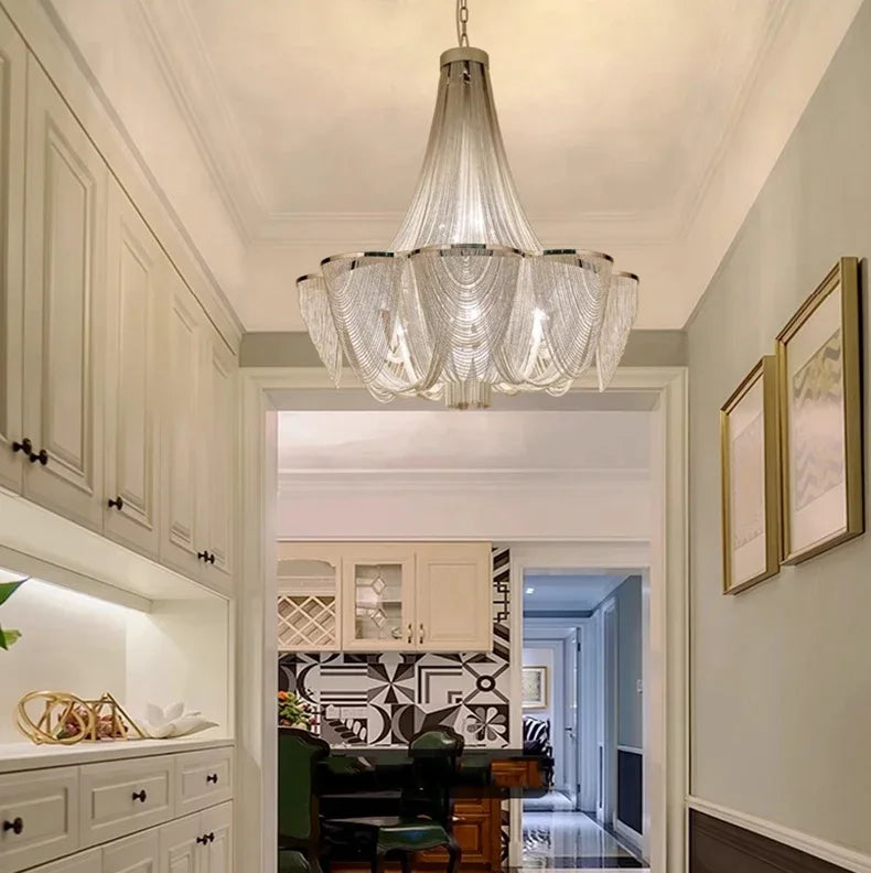 Chandelier hanging in a modern kitchen with white cabinets and a dining area.