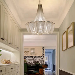Chandelier hanging in a modern kitchen with white cabinets and a dining area.