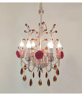Close-up view of a pink and gold chandelier with ceramic rose accents and hanging amber crystals.