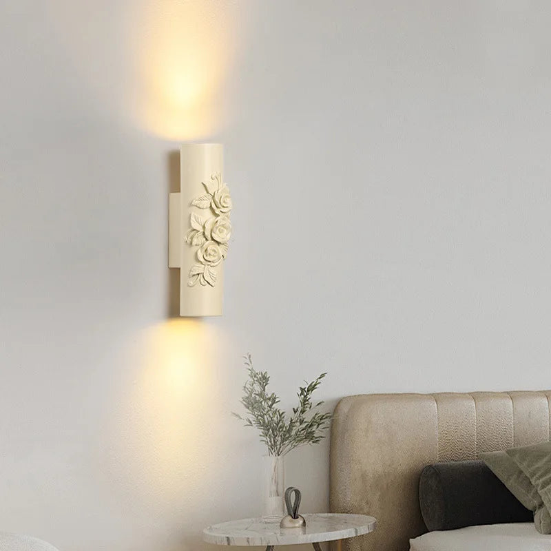 Close-up of a beige cylindrical wall sconce with sculpted roses.