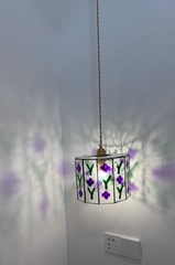 Decorative pendant light with floral design on a white wall.